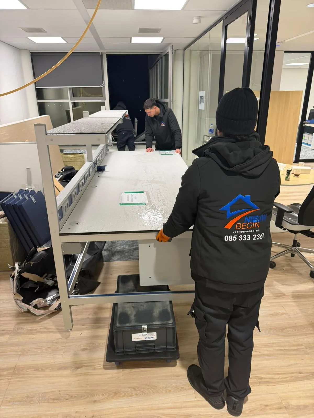 Twee verhuizers demonteren samen een bureau op kantoor