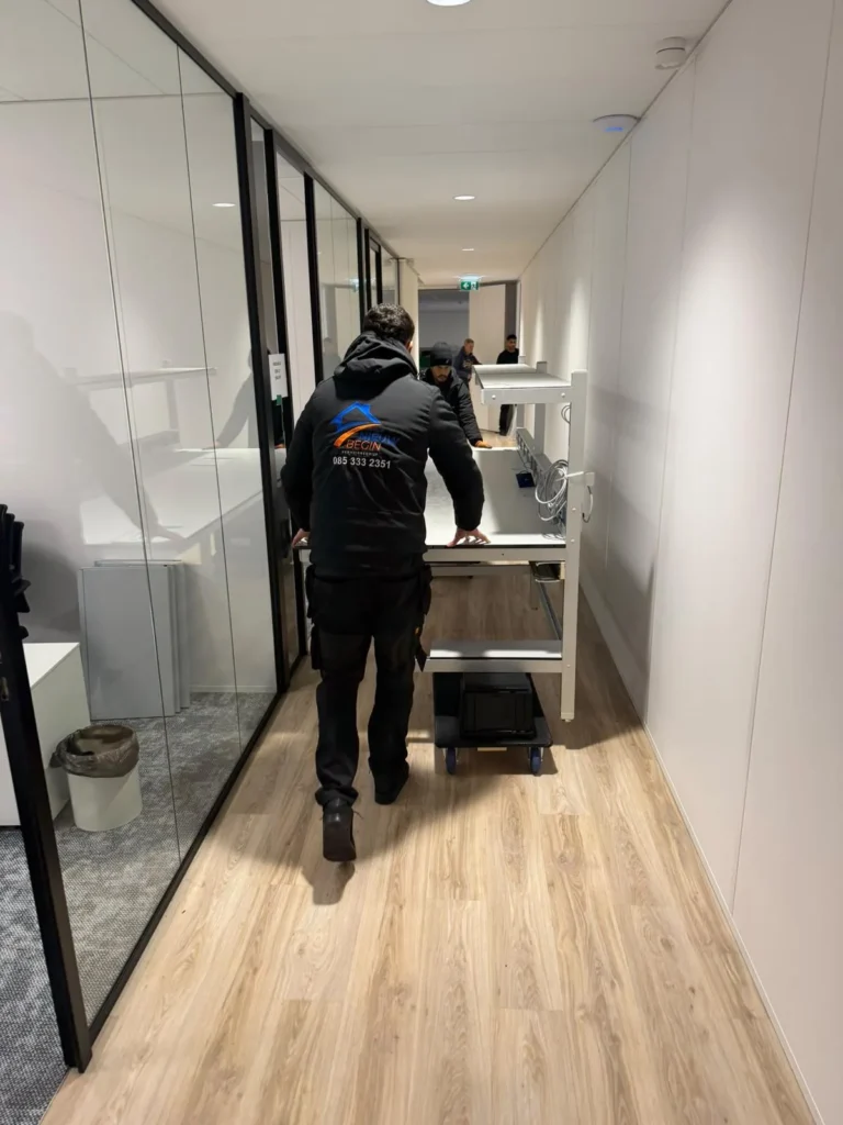 Verhuizer rijdt een bureau op een kar door de kantoorgang