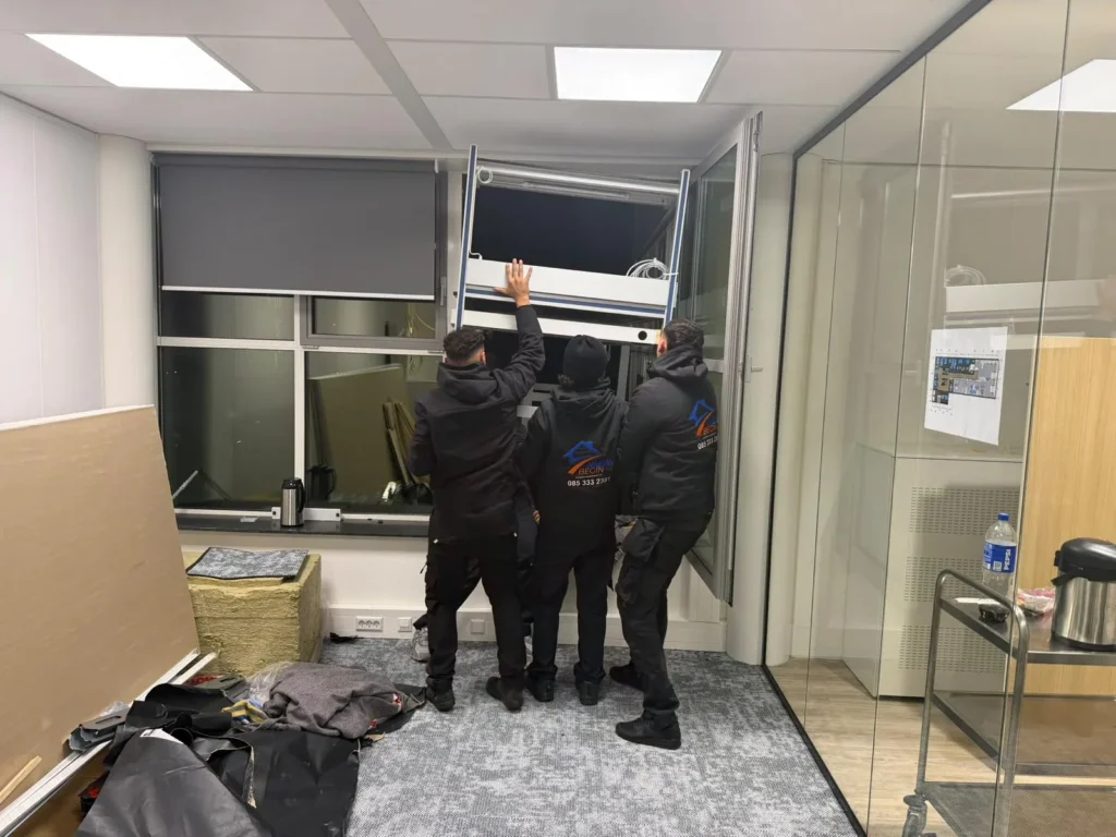 Drie verhuizers aan het werk in een kantoor met glazen wanden