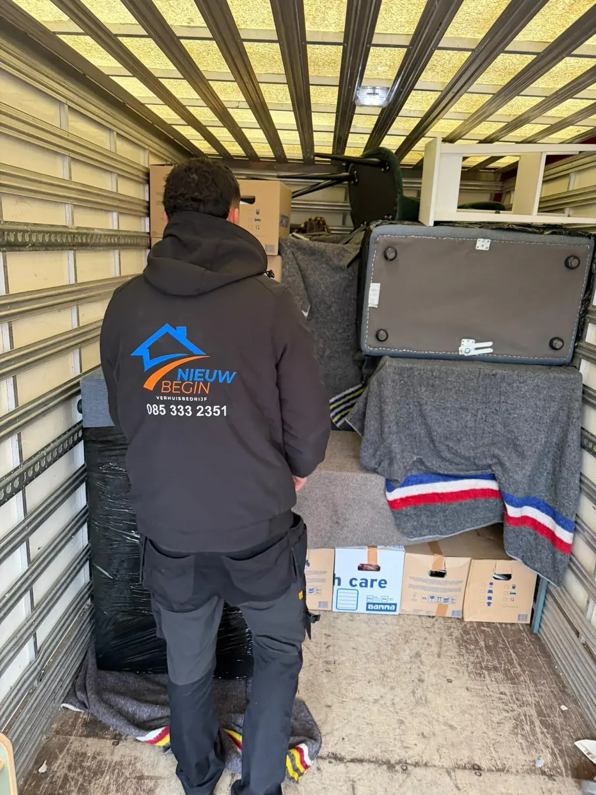 Verhuizer stapelt dozen en meubels in de wagen