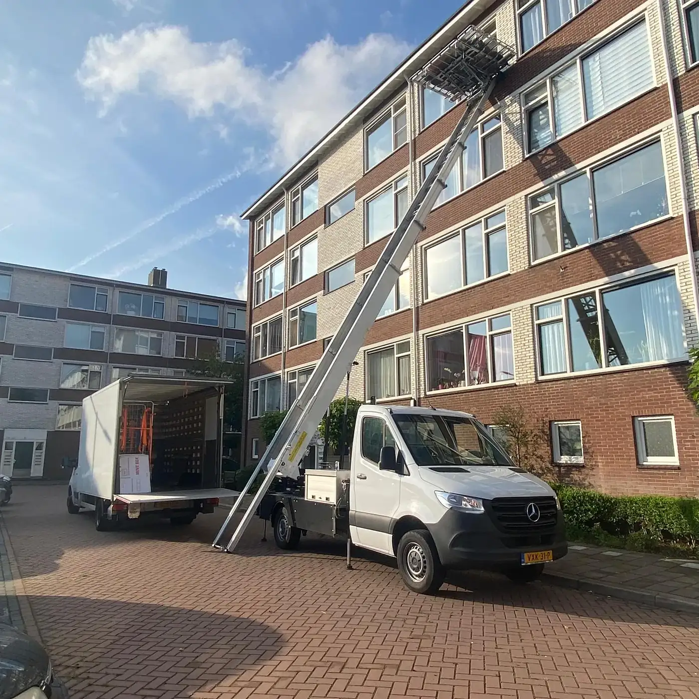 De wagen van Nieuw Begin met de verhuislift tot boven aan een flat