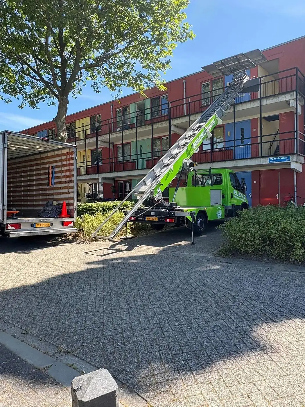 Verhuislift tegen een appartementencomplex, met de wagen ervoor