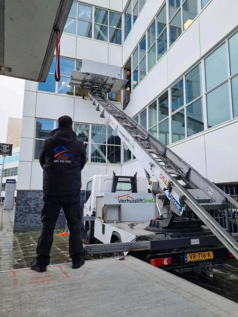 Verhuizer bij de verhuislift tegen een kantoorpand met glazen gevel