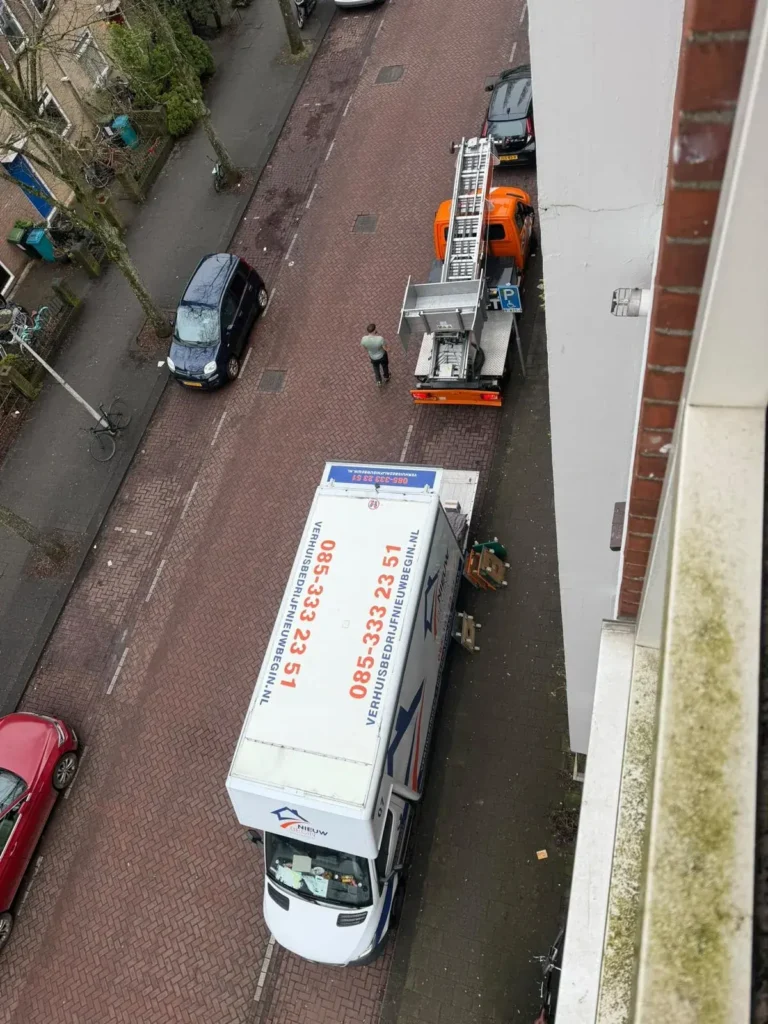 De wagen en de verhuislift van bovenaf in een smalle straat