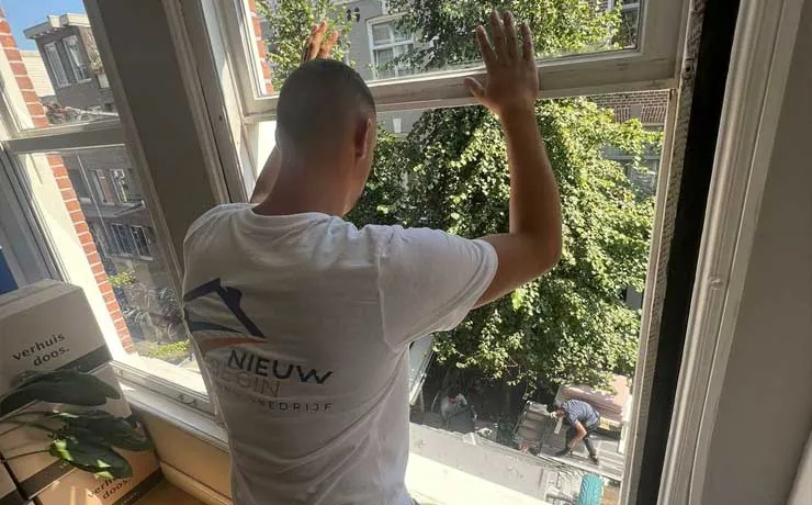 Verhuizer bij het raam van een bovenwoning